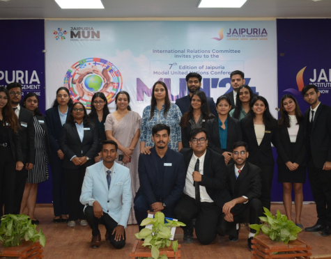 Group of students and organizers posing for a formal group photo on a conference stage at Jaipuria MUN, with a banner reading International Relations Committee and Jaipuria MUN in the background.