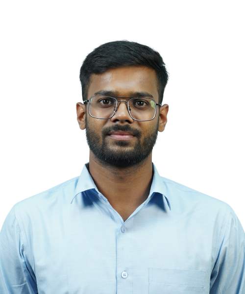 Portrait of a young man with glasses, dark hair and beard, wearing a light blue button-down shirt, facing the camera with a neutral expression, against a plain background.