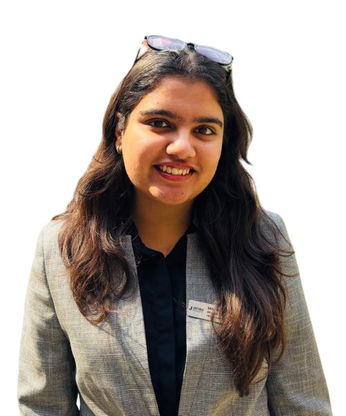 Smiling woman with long dark hair wearing a gray blazer and black top, sunglasses resting on her head.