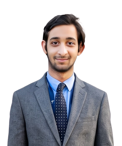 Portrait of a smiling young man in a gray suit, blue shirt, and polka-dotted dark tie, facing the camera.